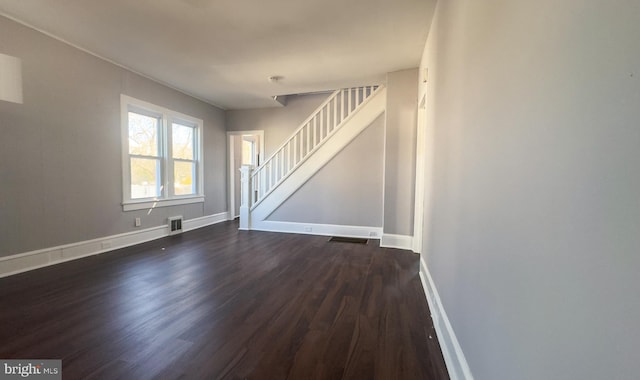 unfurnished living room with baseboards, stairs, visible vents, and dark wood-type flooring