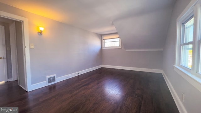 bonus room with baseboards, vaulted ceiling, visible vents, and dark wood finished floors