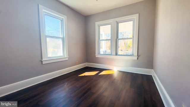 unfurnished room with baseboards and dark wood-type flooring