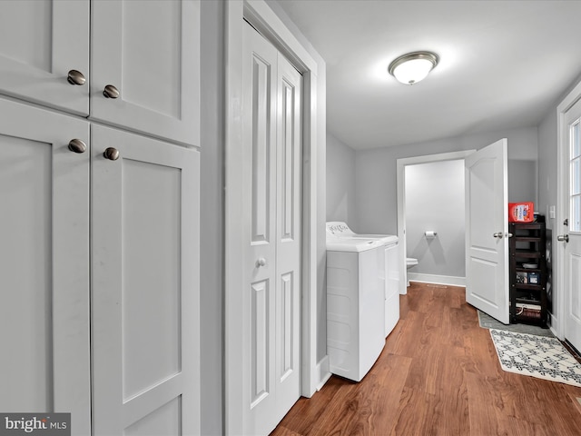 hall featuring washer and dryer, wood finished floors, and baseboards