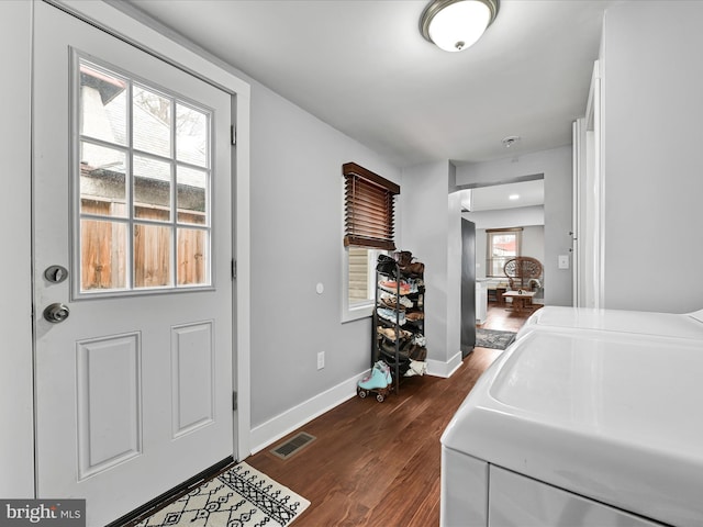 clothes washing area featuring visible vents, dark wood-style floors, washing machine and dryer, baseboards, and laundry area