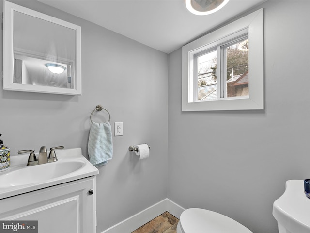 bathroom with toilet, vanity, and baseboards