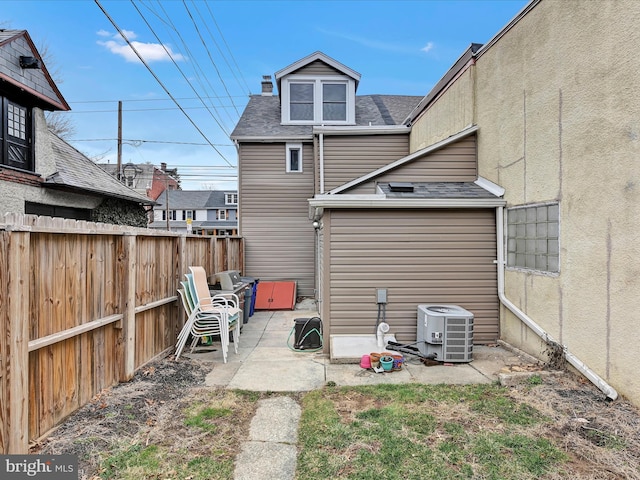 rear view of house featuring central air condition unit, a shingled roof, a patio, and fence