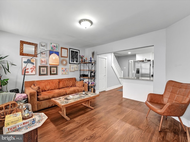 living area with stairway, baseboards, and dark wood-type flooring