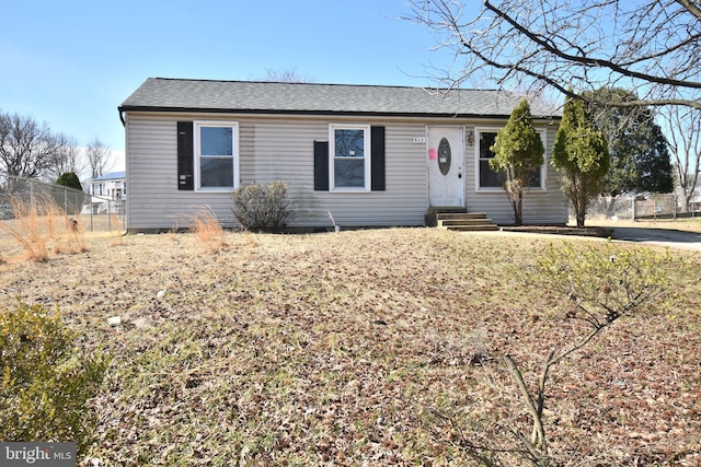 ranch-style home featuring entry steps, a shingled roof, and fence