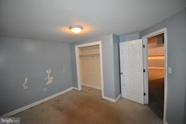 unfurnished bedroom with a closet, concrete floors, and baseboards