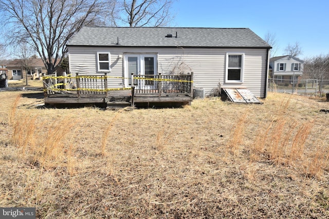 rear view of house with a shingled roof, fence, a deck, and french doors