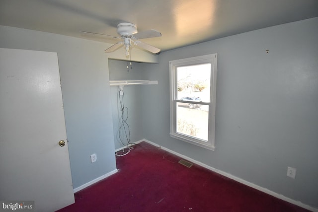 carpeted spare room with ceiling fan, visible vents, and baseboards