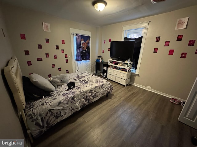 bedroom with baseboards and dark wood-type flooring