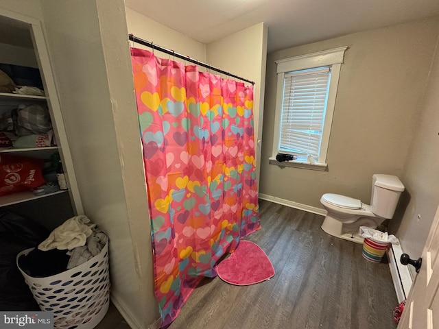 bathroom with baseboards, toilet, a shower with curtain, wood finished floors, and baseboard heating