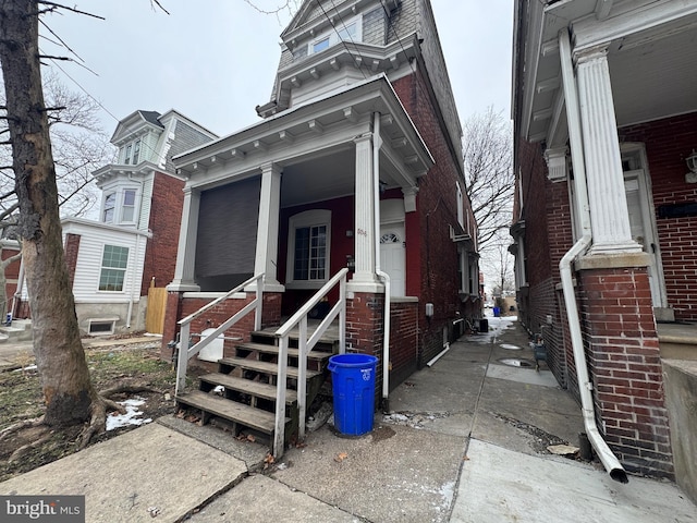 view of front of property featuring entry steps, brick siding, and mansard roof