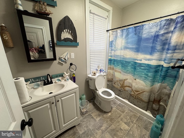 bathroom with toilet, stone finish flooring, vanity, and a shower with curtain