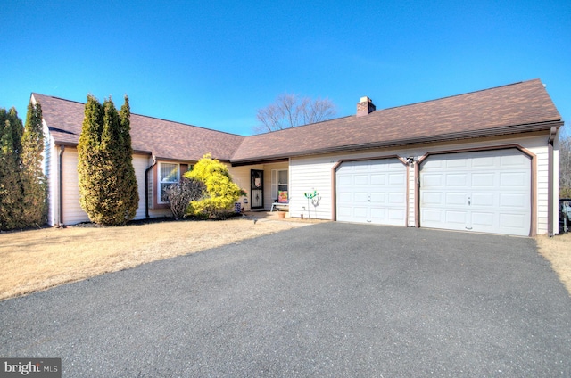 single story home featuring a garage, a chimney, driveway, and roof with shingles