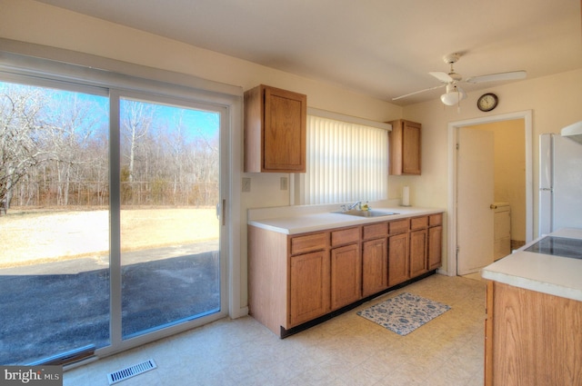 kitchen featuring visible vents, a sink, freestanding refrigerator, light countertops, and light floors