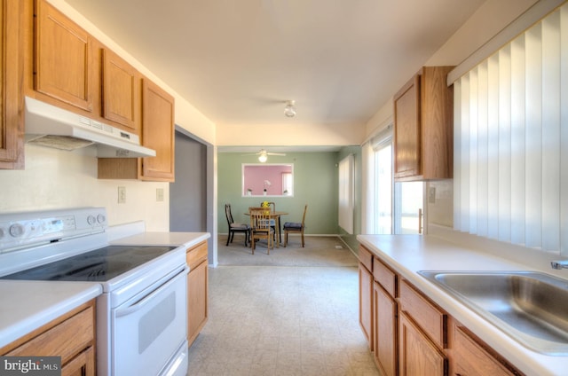 kitchen with under cabinet range hood, light floors, light countertops, electric stove, and a sink