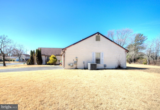 view of side of home featuring cooling unit and a yard