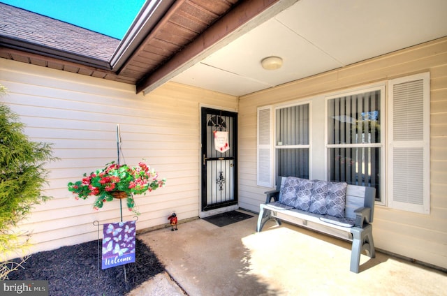 entrance to property with covered porch and roof with shingles