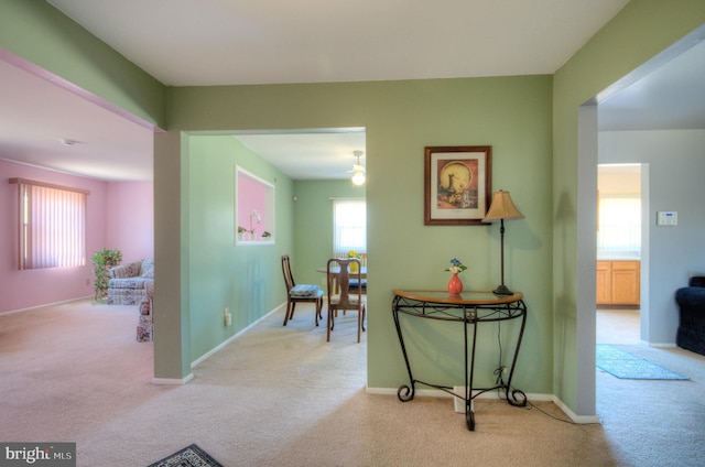 hallway featuring baseboards and light colored carpet