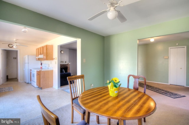 dining space featuring a brick fireplace, a ceiling fan, and baseboards