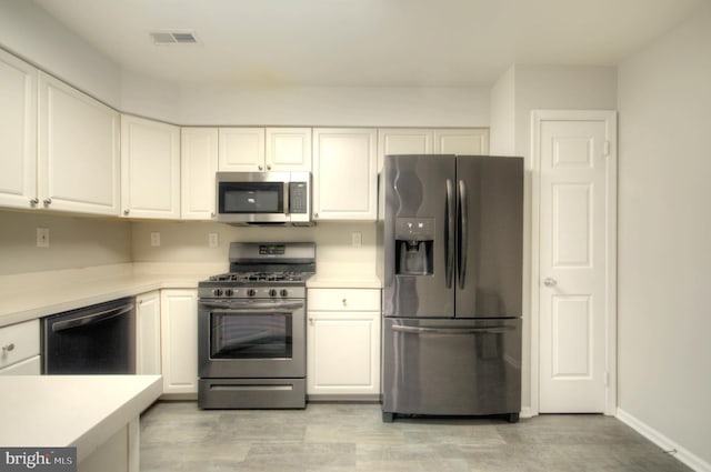 kitchen with visible vents, appliances with stainless steel finishes, white cabinets, and light countertops