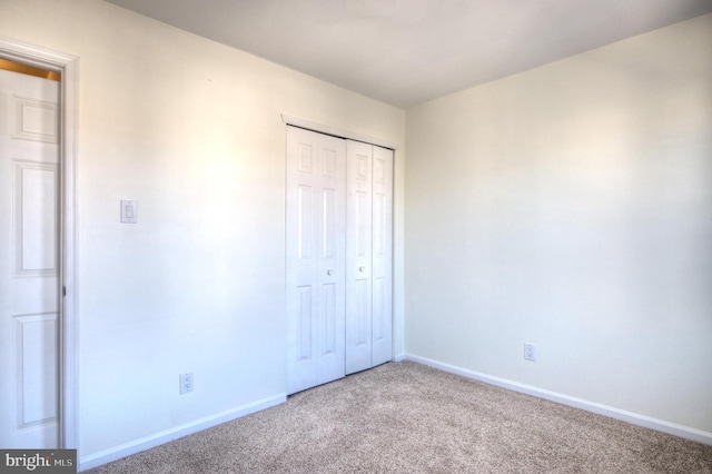 unfurnished bedroom featuring a closet, baseboards, and carpet