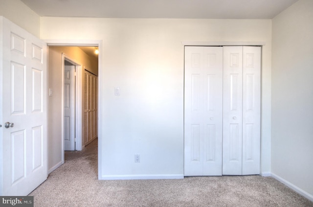 unfurnished bedroom featuring carpet flooring, baseboards, and a closet