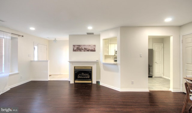 unfurnished living room featuring visible vents, baseboards, wood finished floors, and a fireplace