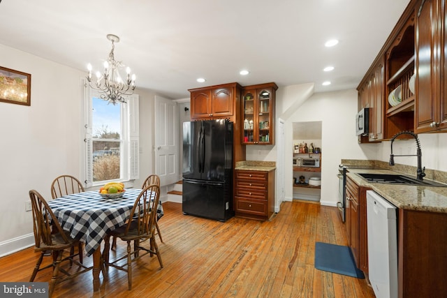 kitchen with white dishwasher, freestanding refrigerator, a sink, light wood-style floors, and stainless steel microwave