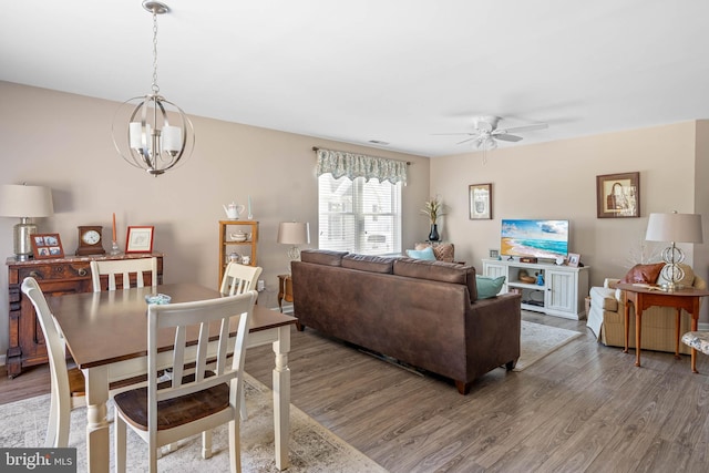 dining area featuring visible vents, light wood-style flooring, and ceiling fan with notable chandelier