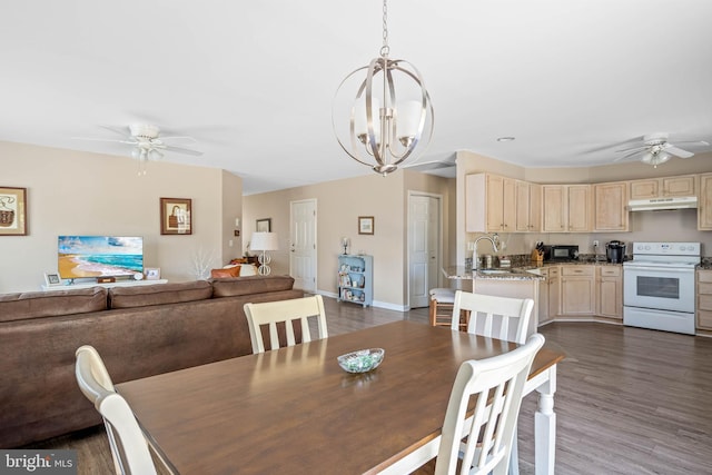 dining space with dark wood finished floors, ceiling fan with notable chandelier, and baseboards