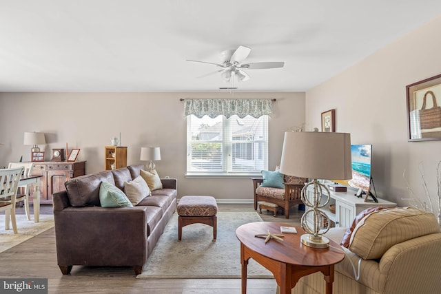 living room featuring baseboards, a ceiling fan, and wood finished floors