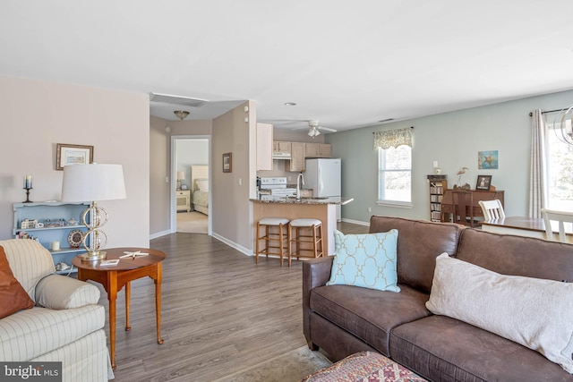 living area with visible vents, baseboards, wood finished floors, and a ceiling fan