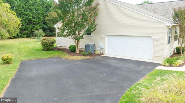 view of side of home with central air condition unit, roof with shingles, a lawn, a garage, and crawl space