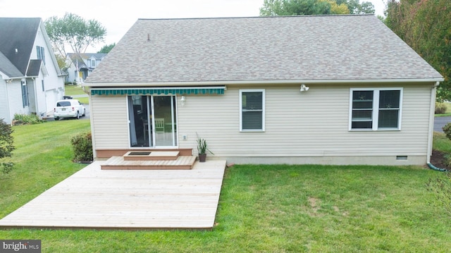 rear view of property featuring crawl space, a wooden deck, a lawn, and roof with shingles