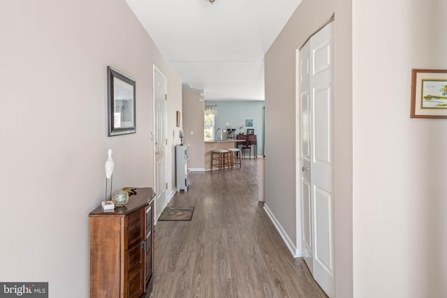 hallway with a sink, baseboards, and wood finished floors