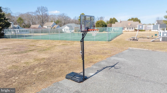 view of tennis court with community basketball court, a yard, and fence