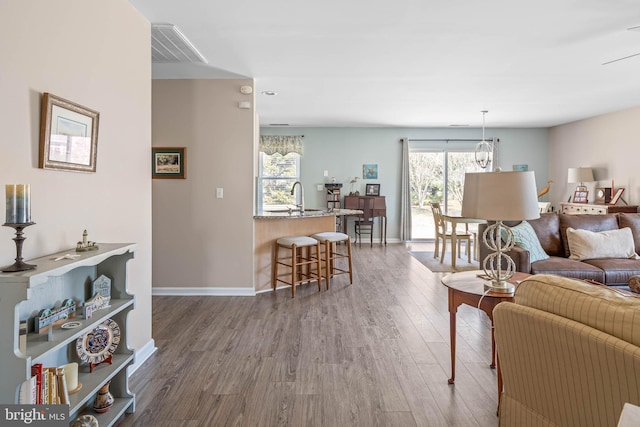 living area featuring a chandelier, baseboards, and wood finished floors