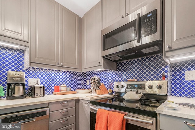 kitchen with appliances with stainless steel finishes, gray cabinets, and decorative backsplash