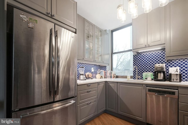 kitchen featuring tasteful backsplash, appliances with stainless steel finishes, a sink, and gray cabinetry