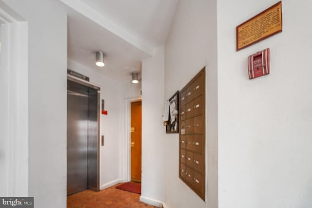 hall featuring baseboards, mail area, and elevator