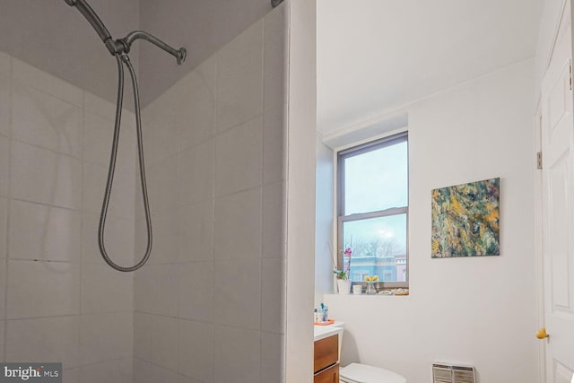 bathroom featuring visible vents, a tile shower, vanity, and toilet