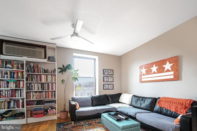 living area featuring a wall unit AC, ceiling fan, and wood finished floors