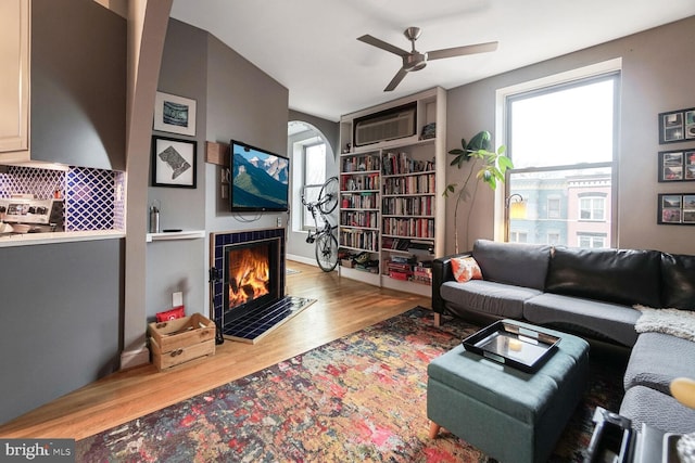 living room with plenty of natural light, a fireplace, wood finished floors, and a wall mounted AC