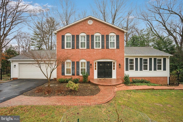 colonial house with a garage, driveway, a front lawn, and fence