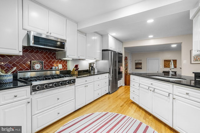 kitchen with stainless steel appliances, light wood finished floors, a sink, and white cabinetry