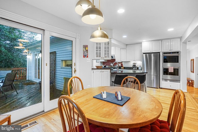 dining area with light wood-style flooring, visible vents, and recessed lighting