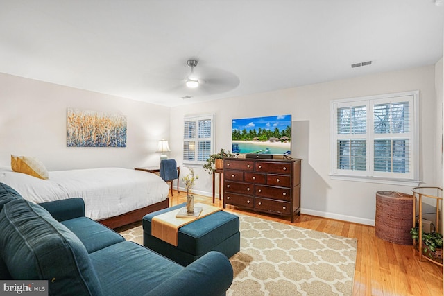 bedroom with ceiling fan, wood finished floors, visible vents, and baseboards