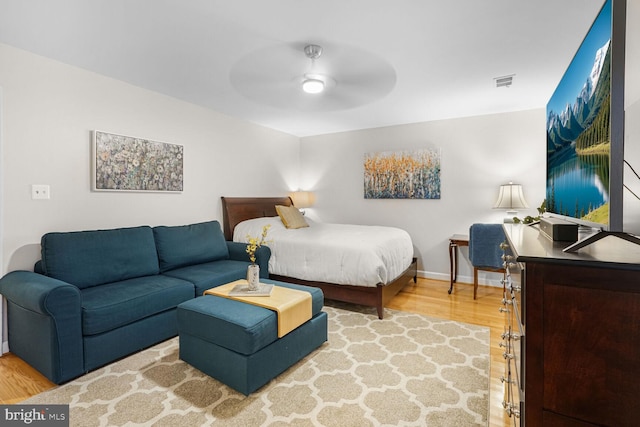 bedroom featuring ceiling fan, wood finished floors, visible vents, and baseboards