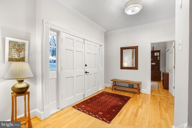 foyer featuring crown molding, baseboards, and wood finished floors