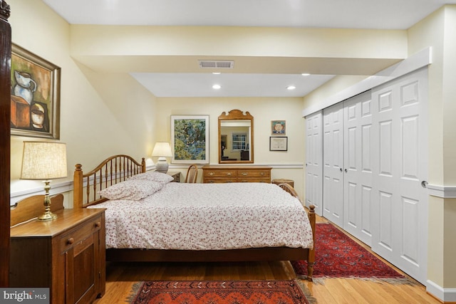 bedroom with a closet, visible vents, wood finished floors, and recessed lighting